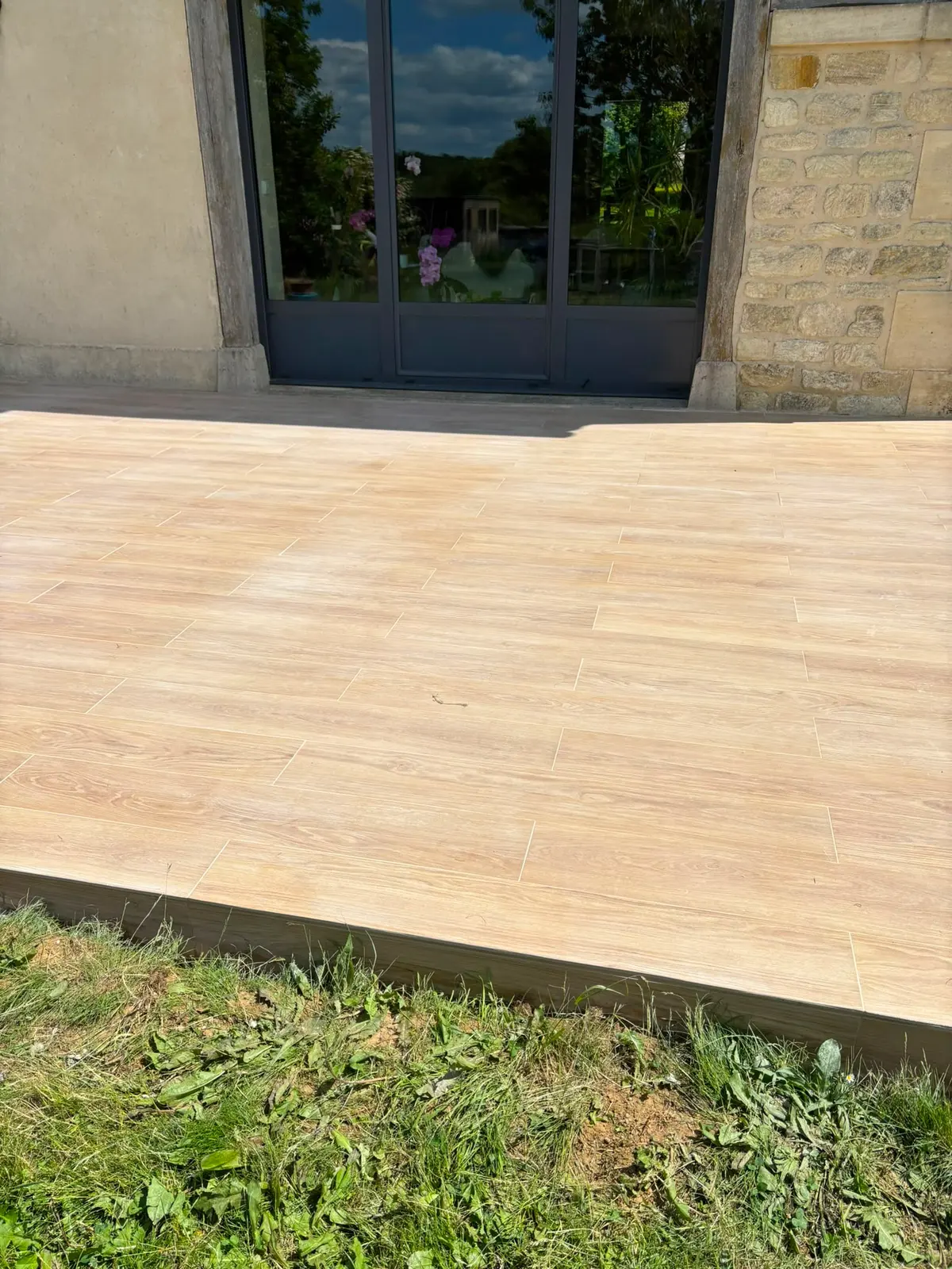 Terrasse en dalles claires devant la maison, après travaux